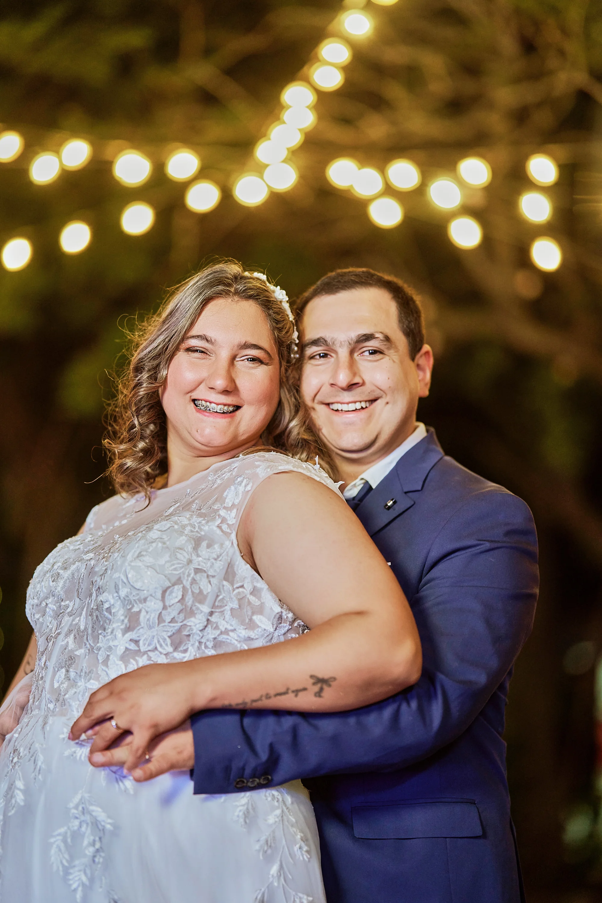 Abrazo de novios bajo guirnalda de luces nocturna — Luréa Studio