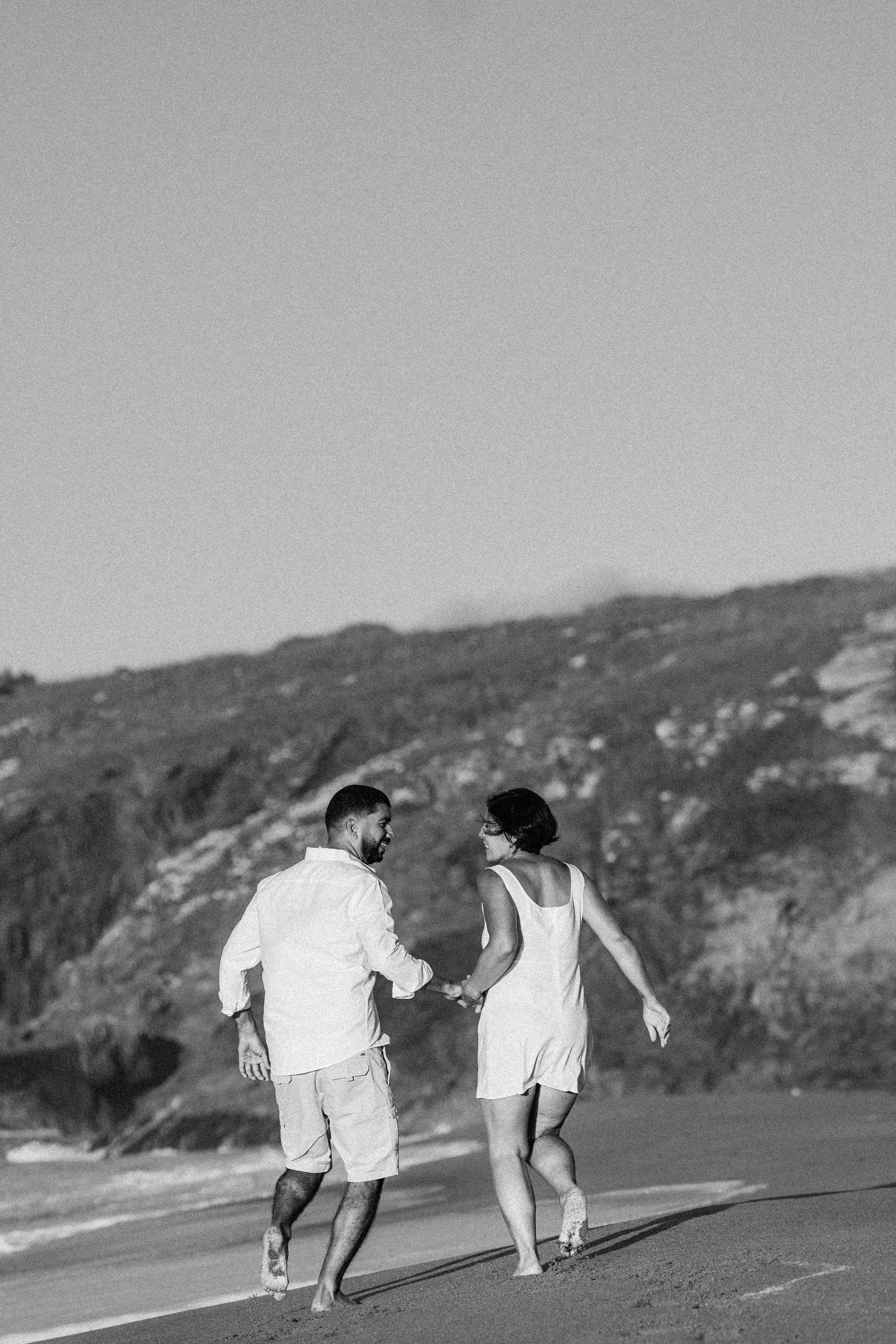 Pareja de novios caminando por la playa, blanco y negro — Luréa Studio