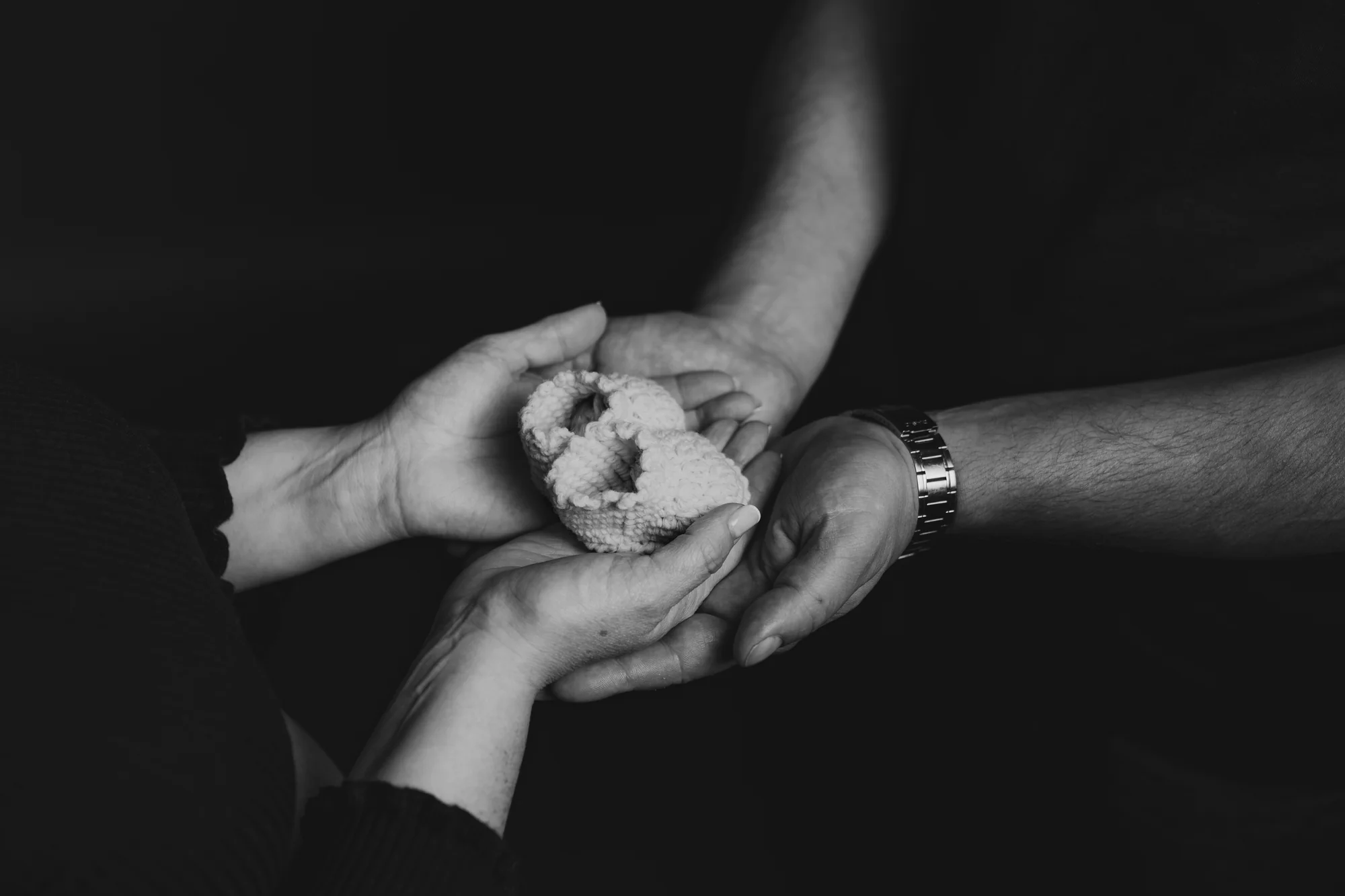Manos sosteniendo botitas de bebé, blanco y negro — Luréa Studio