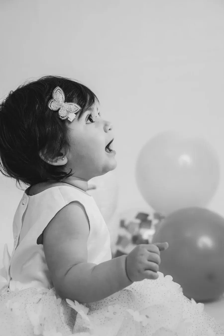 Bebé con moño de mariposa junto a globos