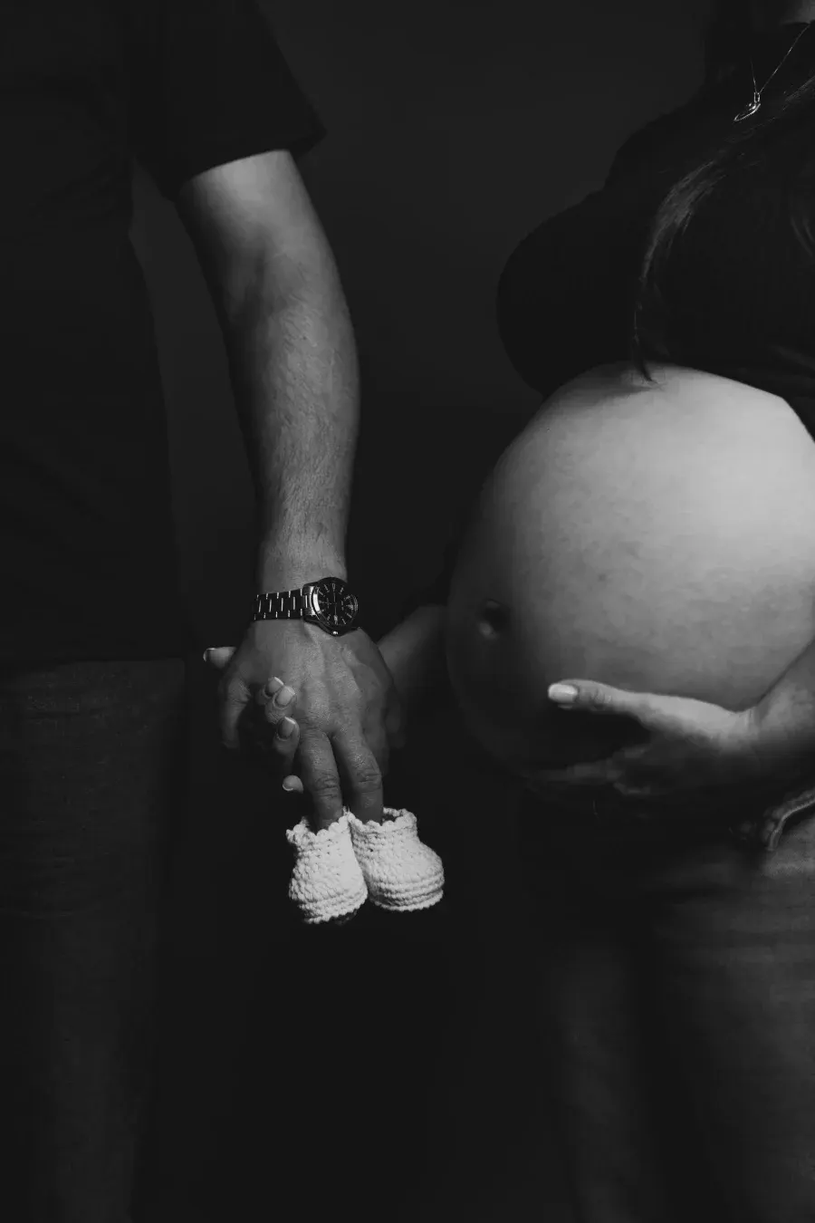 Manos de la pareja sosteniendo botitas de bebé